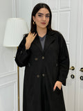 Woman wearing a Black Shamwa Trench Abaya Set standing in front of a white door.