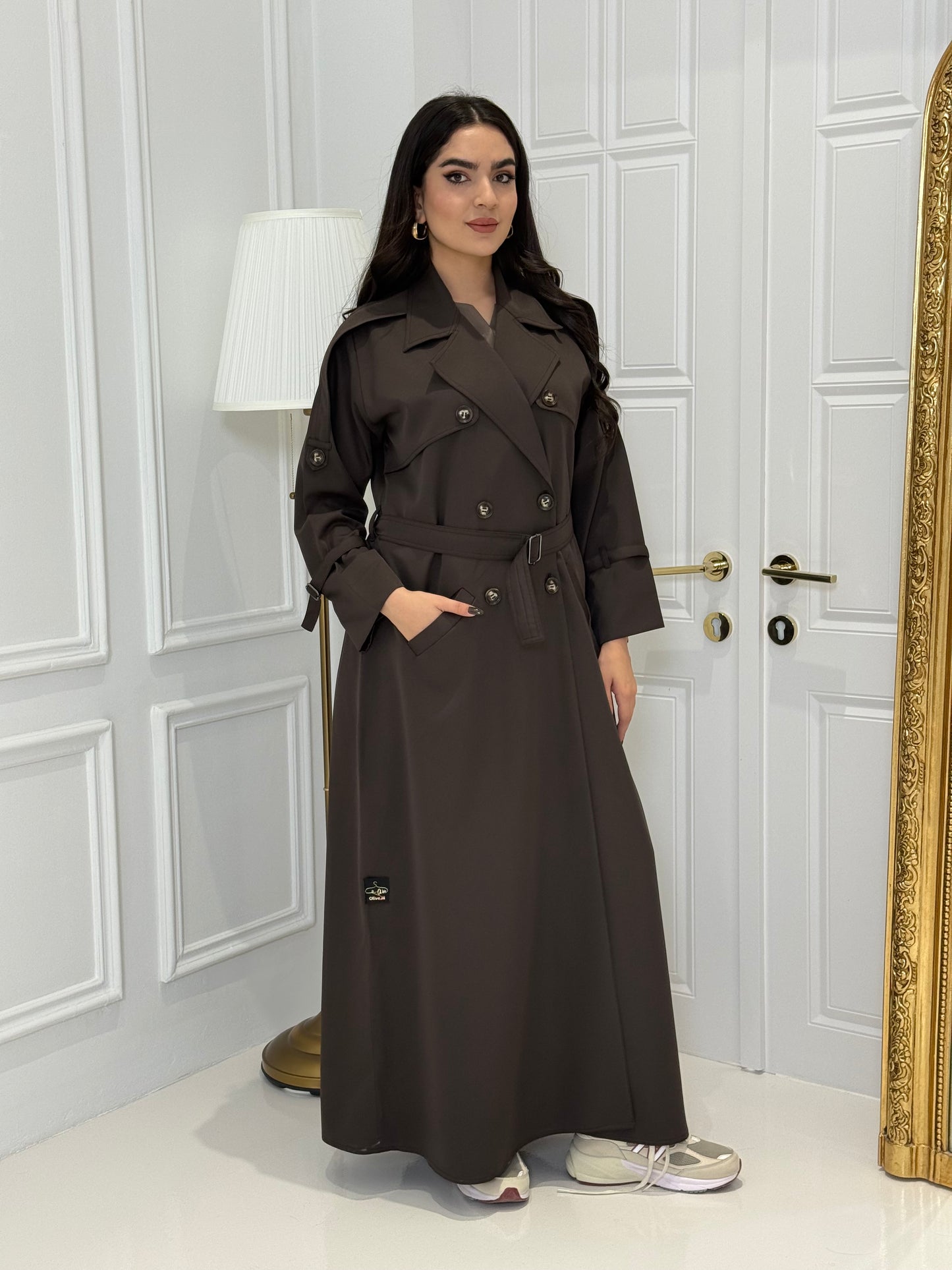Person wearing a long Dark Brown Linen coat Abaya Set standing in front of a white door with gold handles.