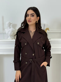 Person wearing a long Dark maroon Linen Abaya trench coat Set standing in front of a white door with gold handles.