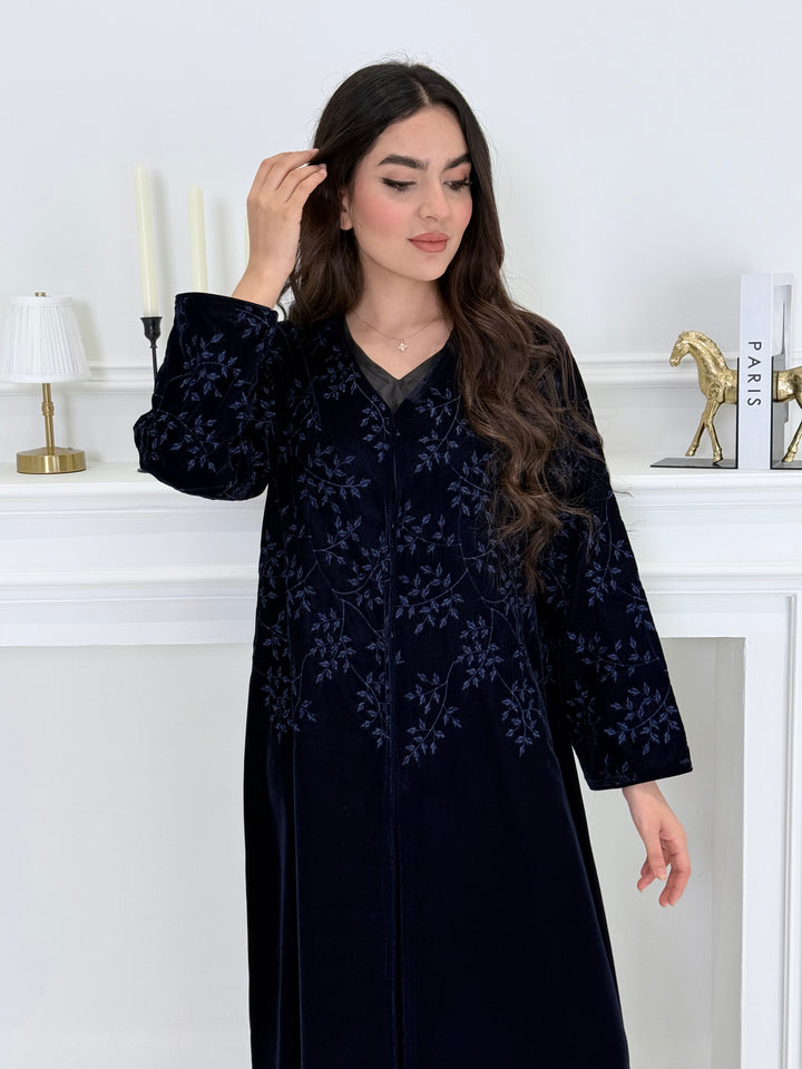 Woman wearing a Navy Blue Velvet Embroidered Abaya with floral patterns in a minimalistic setting