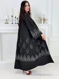 Woman wearing a Premium Silver Embroidered Black Abaya dress with lace details made from Nida fabric and matchhing sheila in a white room.