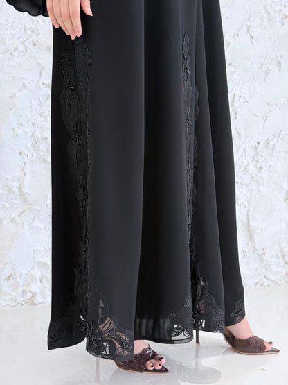 Person wearing a Premium Luxury Hand-Embellished Black Abaya outfit made from Nida fabric, standing on a textured white surface