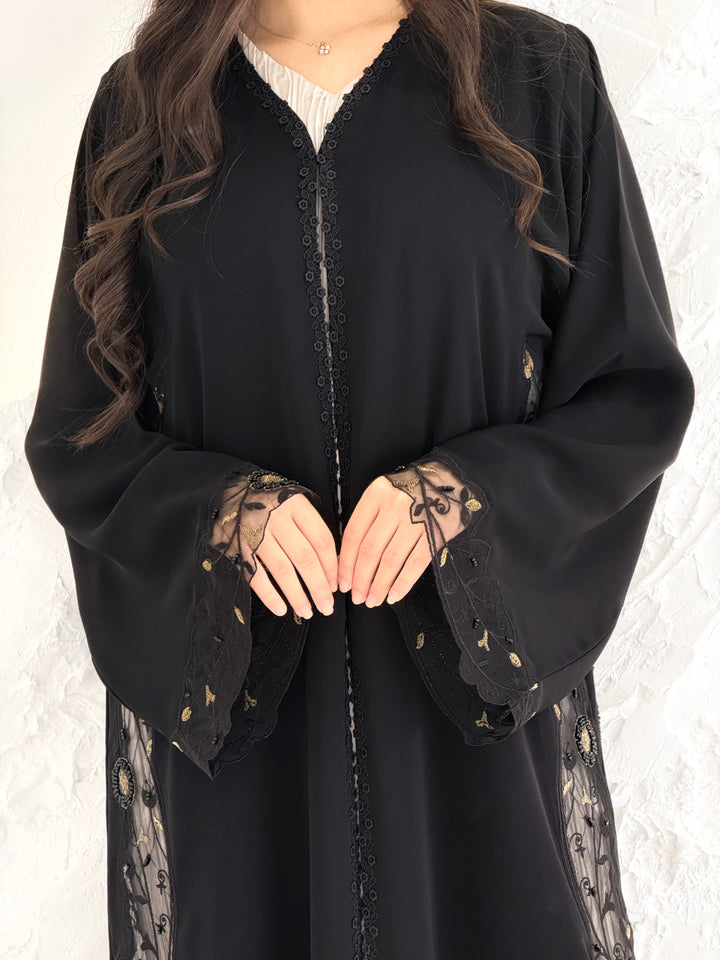 Person wearing a Premium Gold Hand-Embellished Abaya made from Nida fabric and Sheer Mesh Panel outfit on a white background