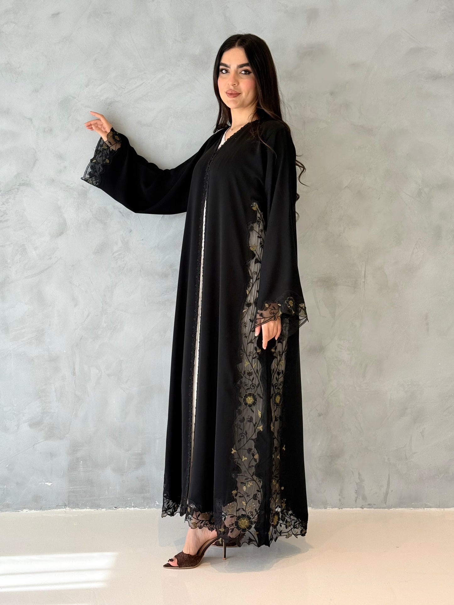 Person wearing a Premium Gold Hand-Embellished Abaya made from Nida fabric and Sheer Mesh Panel outfit on a white background