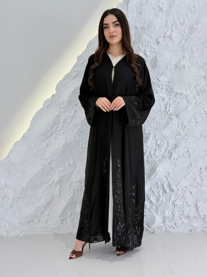 Woman in a long Premium Black Hand-Embellished Chiffon Abaya standing on a snowy landscape