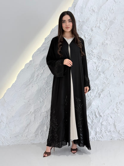 Woman in a long Premium Black Hand-Embellished Chiffon Abaya standing on a snowy landscape