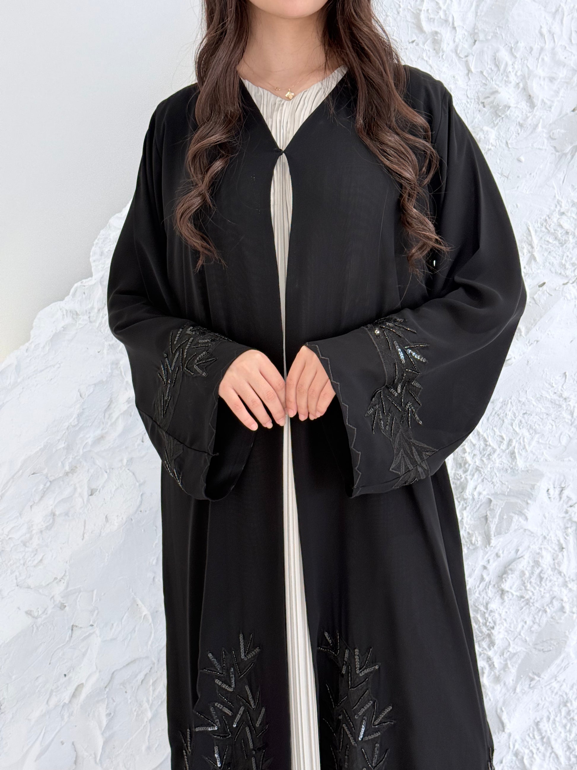 Woman in a long Premium Black Hand-Embellished Chiffon Abaya standing on a snowy landscape