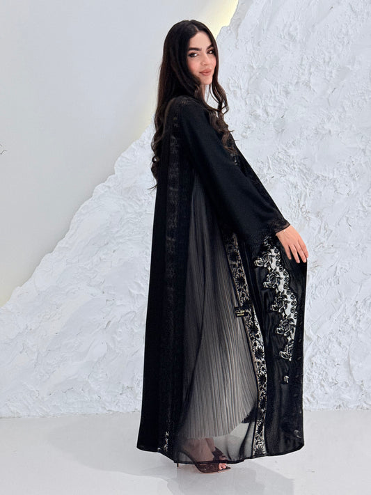Woman wearing a Premium Black Hand-Embellished Abaya against a white textured wall