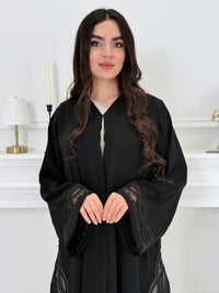 Woman wearing a  Premium Black Abaya with Silver Plissé Panel on a light gray background