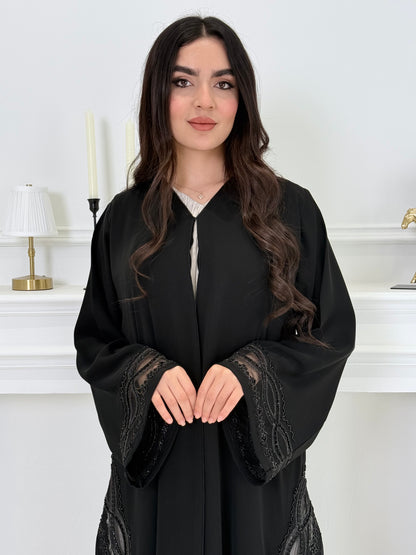 Woman wearing a  Premium Black Abaya with Silver Plissé Panel on a light gray background