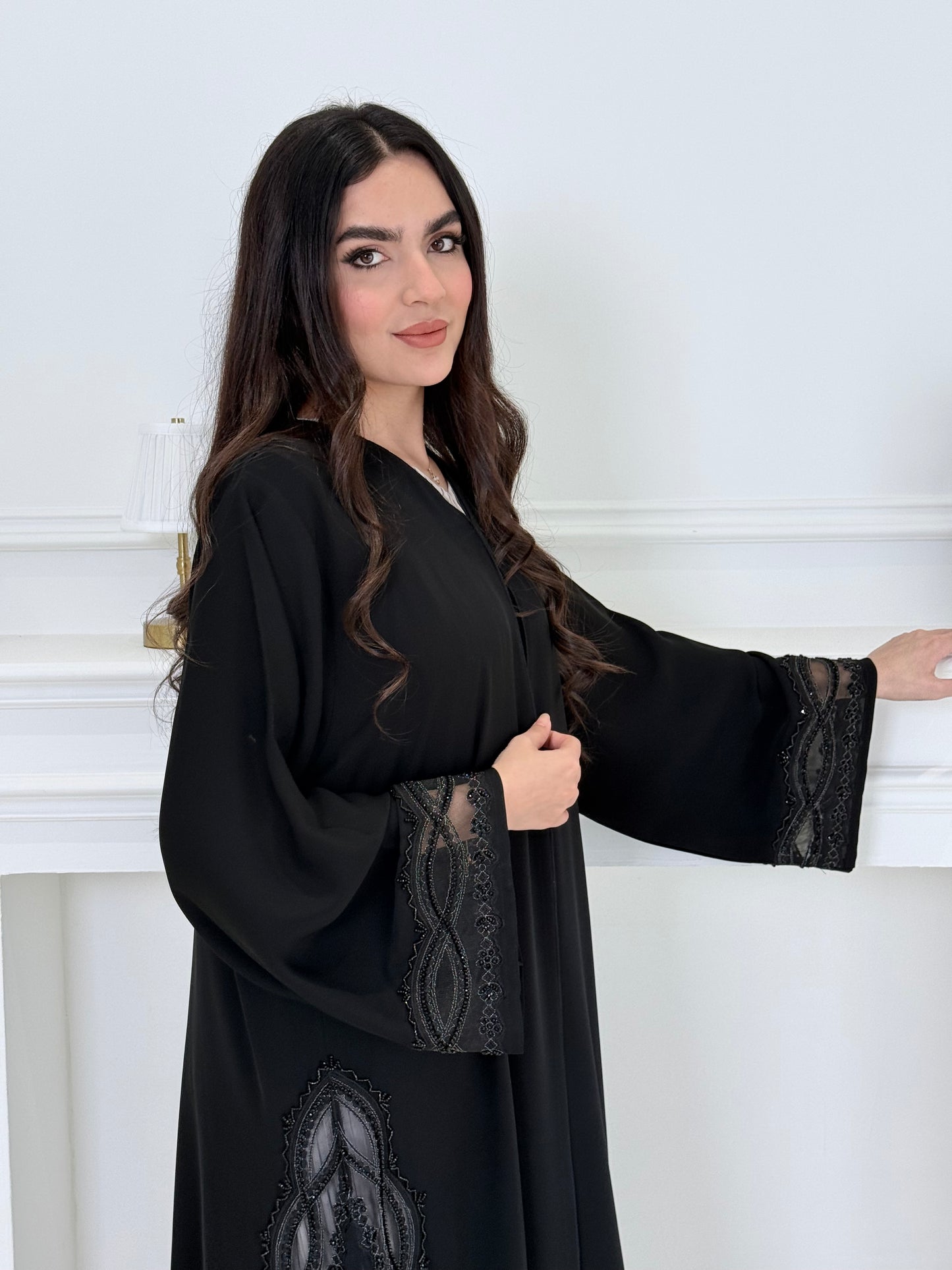 Woman wearing a  Premium Black Abaya with Silver Plissé Panel on a light gray background