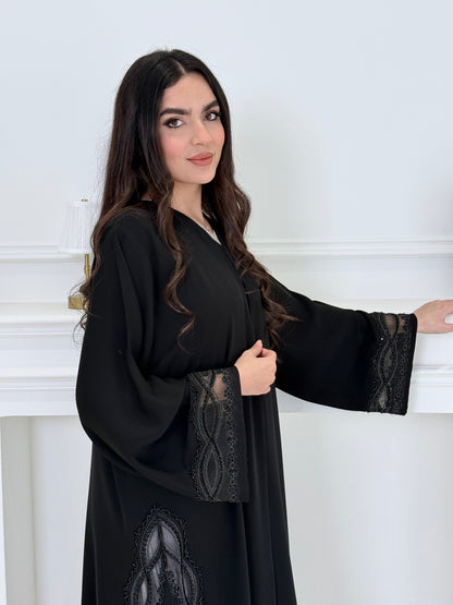 Woman wearing a  Premium Black Abaya with Silver Plissé Panel on a light gray background