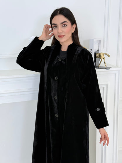 Woman wearing a Black Velvet Trench Abaya coat in a minimal white interior setting