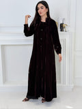 Woman wearing a long Dark Chocolate Velvet Trench Abaya coat in a minimal white room