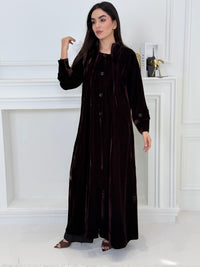 Woman wearing a long Dark Chocolate Velvet Trench Abaya coat in a minimal white room