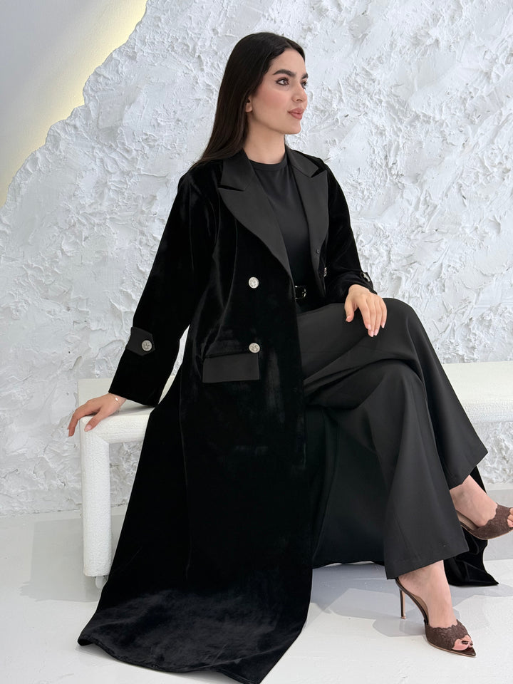 Woman wearing a Premium Black Velvet  coat abaya on a light gray background