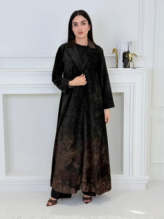A woman wearing a in Black Velvet Abaya with Bronze & Maroon Details a white room
