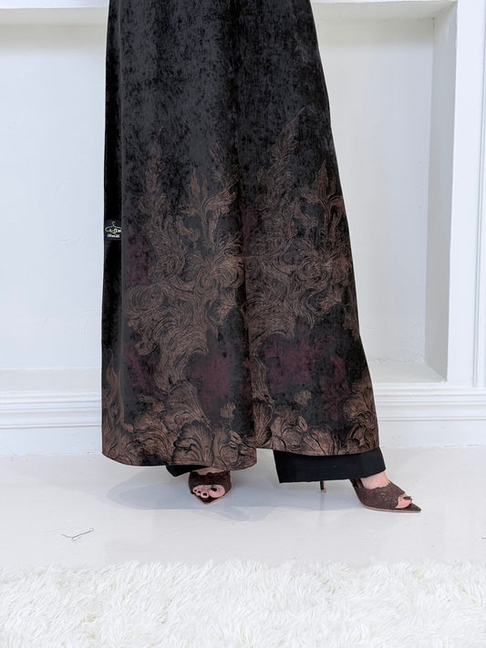 A woman wearing a in Black Velvet Abaya with Bronze & Maroon Details a white room