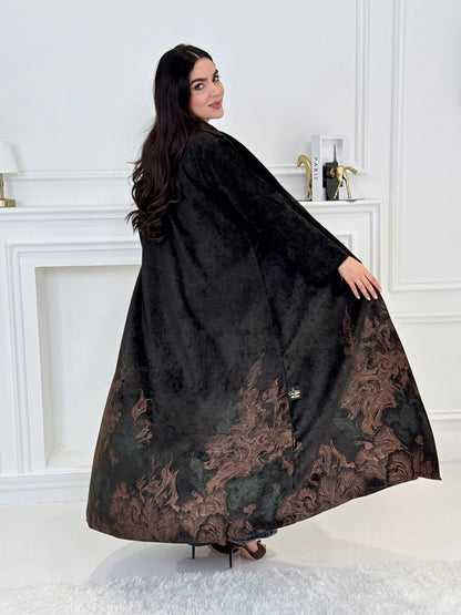A woman wearing a in Black Velvet Abaya with brown & green Details a white room