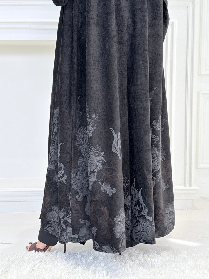 A woman wearing a in Black Velvet Abaya with silver and grey Details a white room
