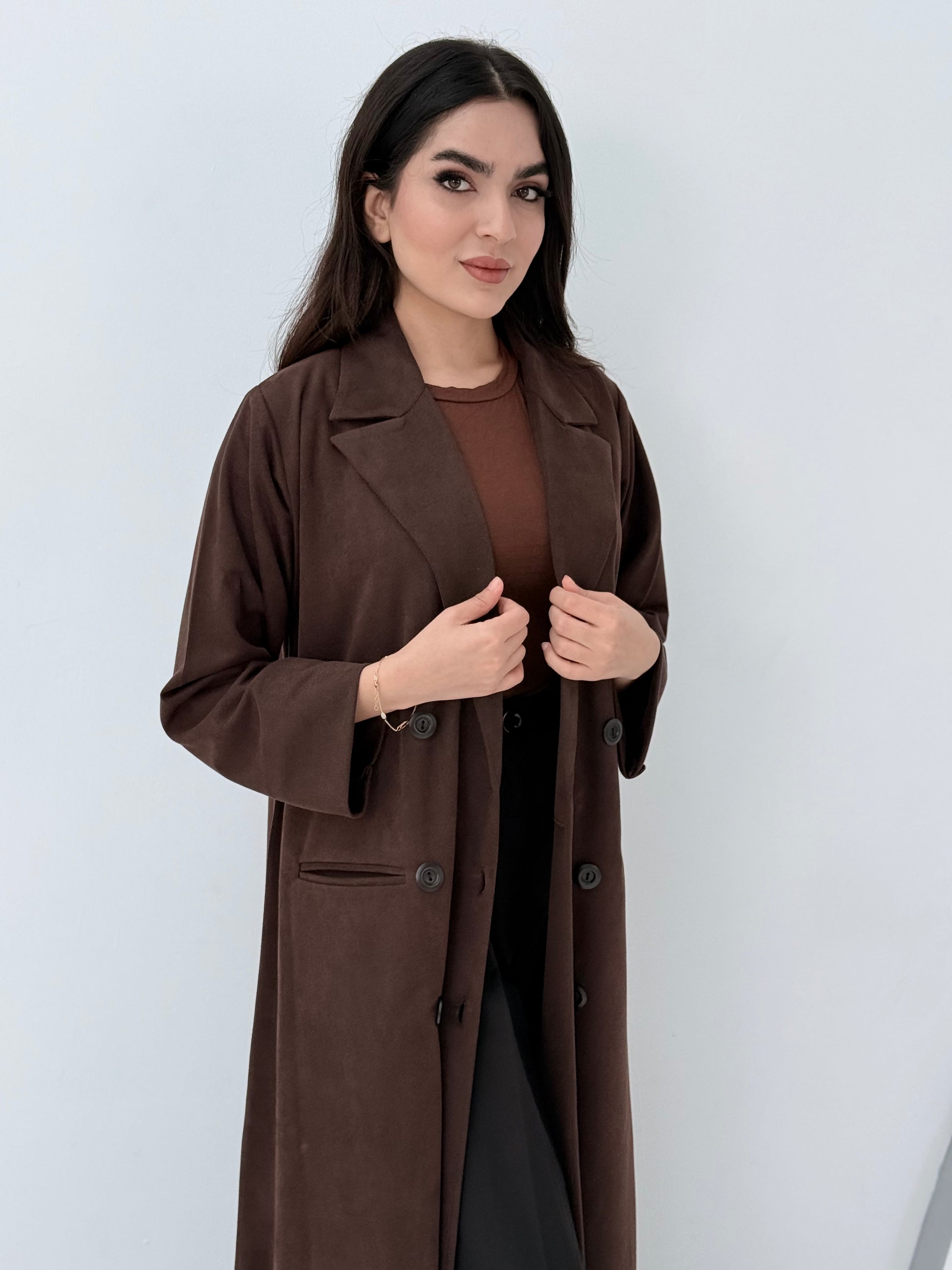 Woman wearing a Premium  dark brown Shamwa coat abaya against a white background