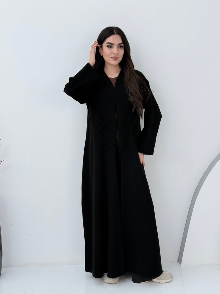 Woman wearing a long Premium black Crepe Abaya with Pleated Waist dress on a white background