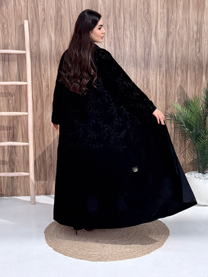 a woman wearing Premium Black Velvet Abaya with Tone-on-Tone Vine floral Embroidery on a pink background