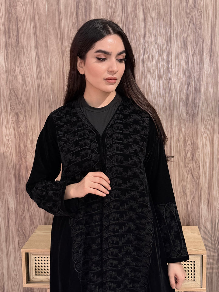 Woman wearing Premium Black Velvet Abaya with Front Embroidery on a wooden floor