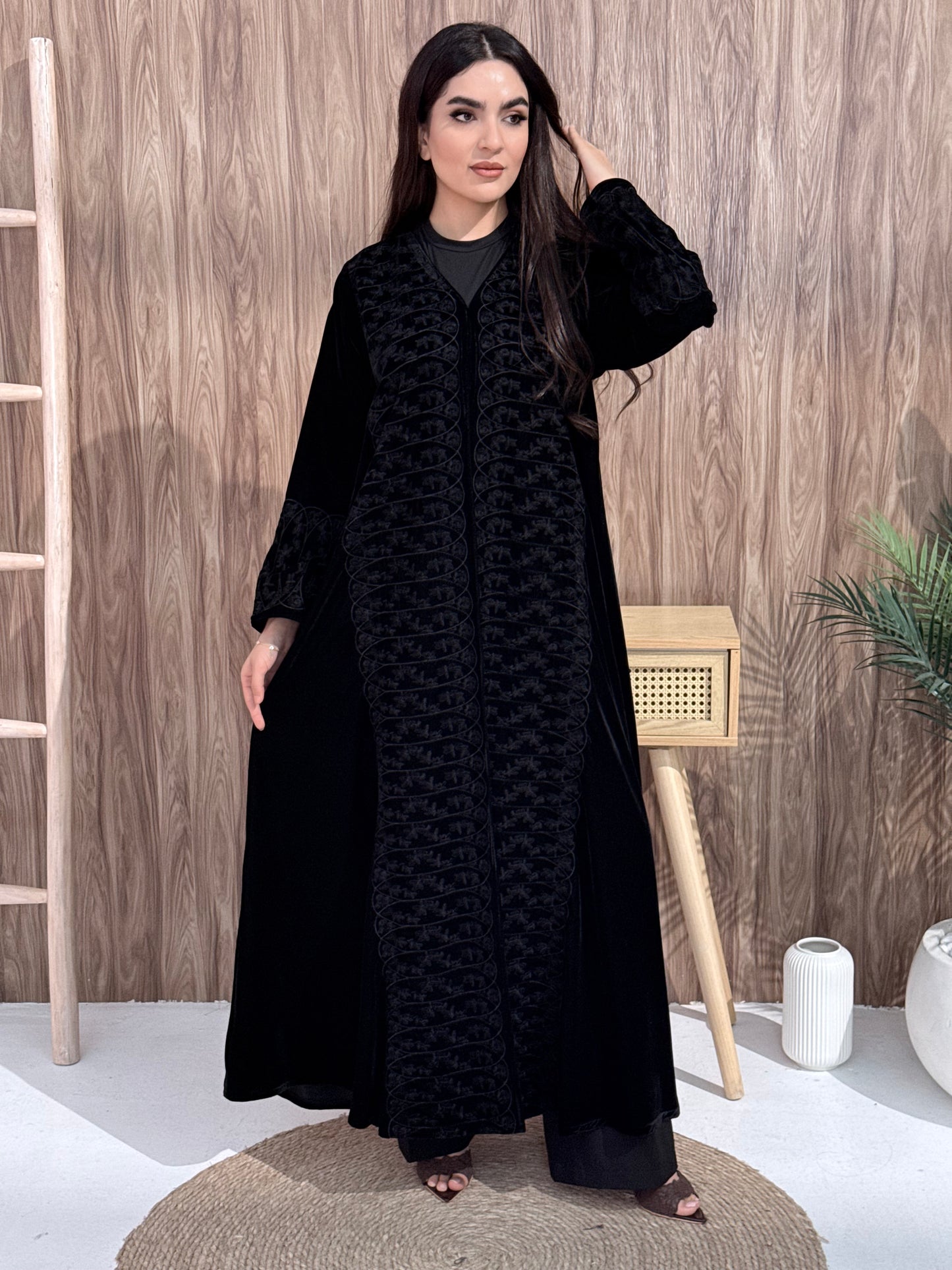 Woman wearing a black dress with a geometric pattern on a wooden floor.