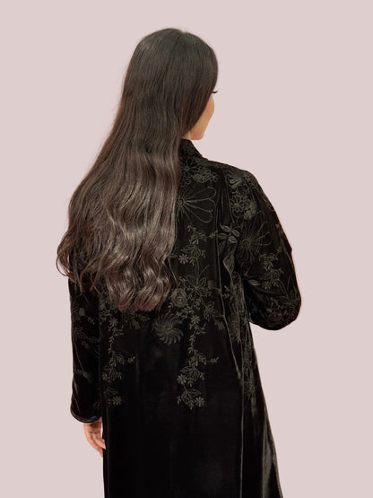 a lady wearing Premium Black Velvet Abaya with Floral Embroideryon a pink background