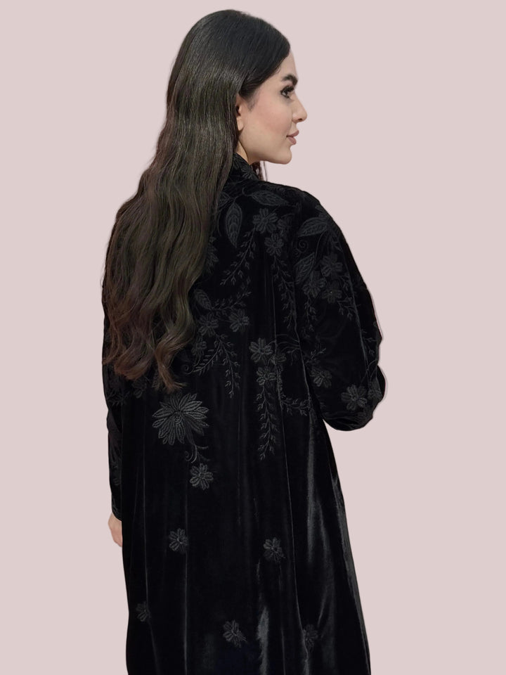 Woman wearing a Premium Black Velvet Abaya with Embroidery against a light pink background