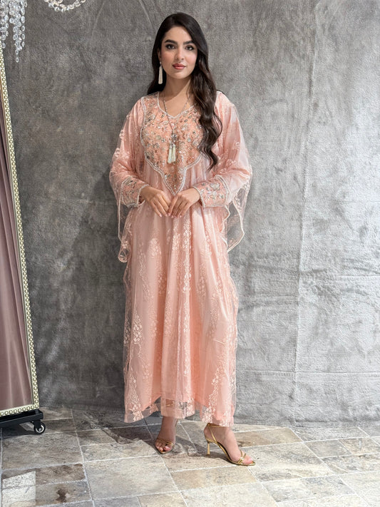 Woman wearing a Pink French Lace Tulle jalabiya dress against a gray textured wall.