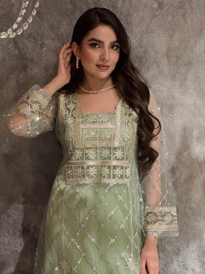 Woman in a luxury mint green Embroidered Tulle kaftan Dress with Stone Detailing standing on a marble floor