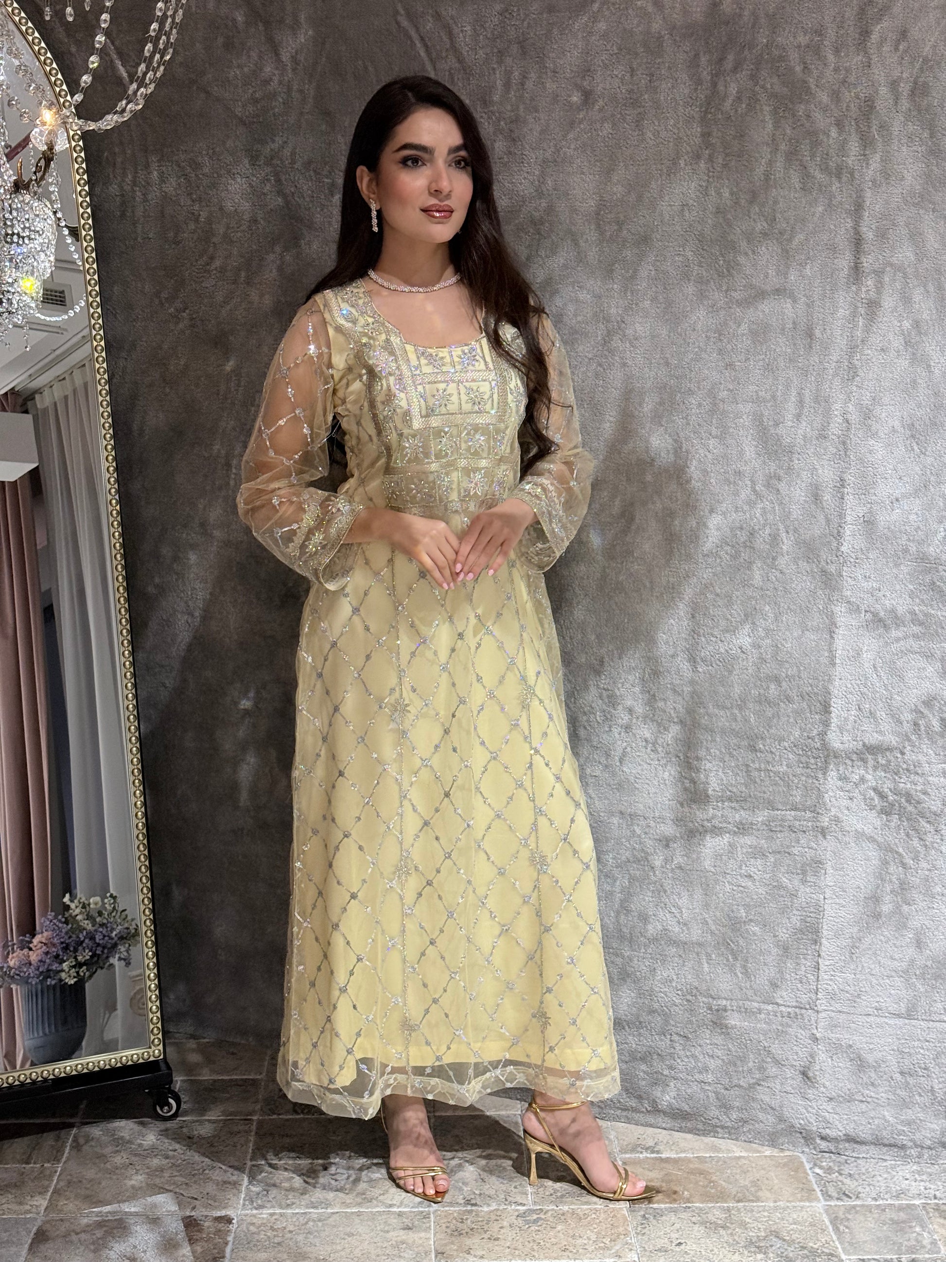 Woman in a luxury pale yellow Embroidered Tulle kaftan Dress with Stone Detailing standing on a marble floor