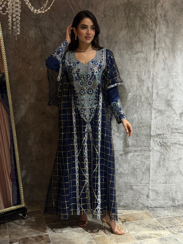 Woman wearing a long, Navy Blue Emirati design tulle jalabiya dress, standing on a marble floor.