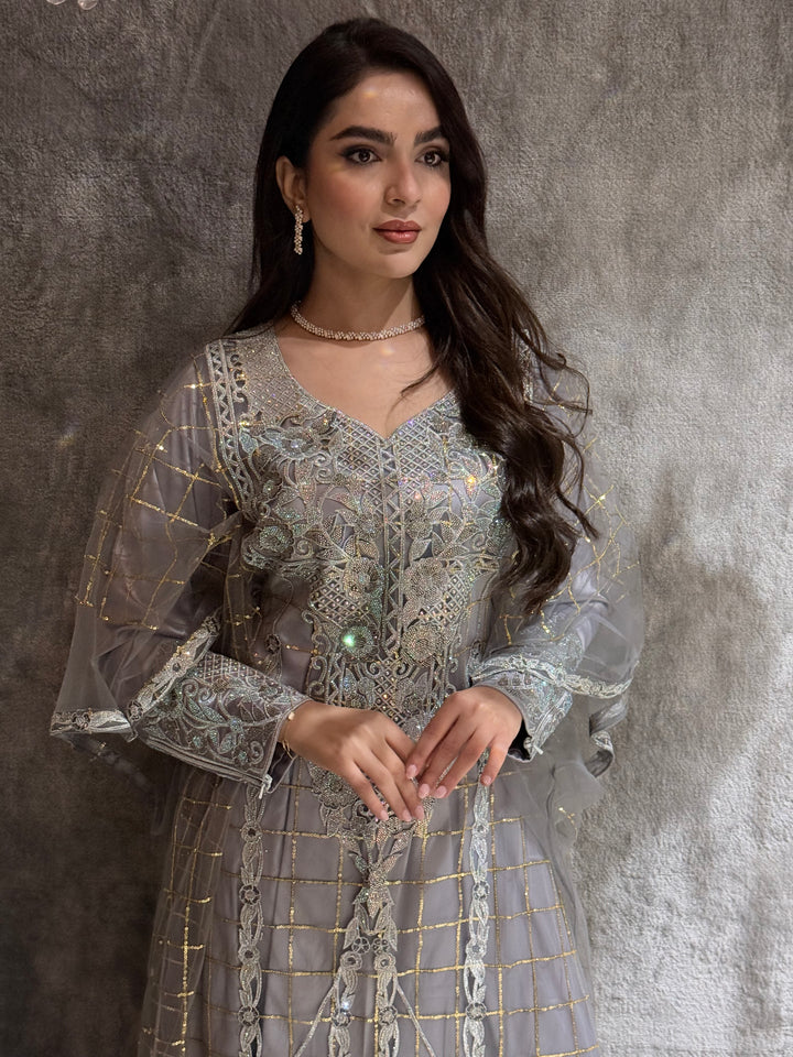 Woman in a long, Silver Grey Emirati Design Tulle jalabiya Dress standing in front of a mirror on a marble floor.