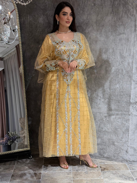 Woman in a Yellow Emirati Design Tulle kaftan Dress standing in front of a mirror on a gray floor.