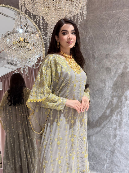 Woman in a Grey Luxury Embroidered Kaftan Dressstanding in front of a textured wall.