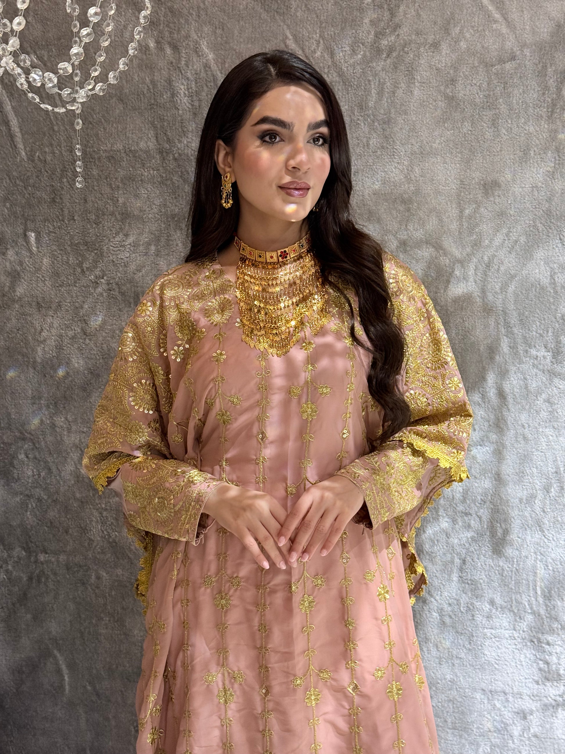 Woman wearing a traditional Pink Luxury Embroidered Kaftan Dress outfit with gold and pink embroidery on a gray background 