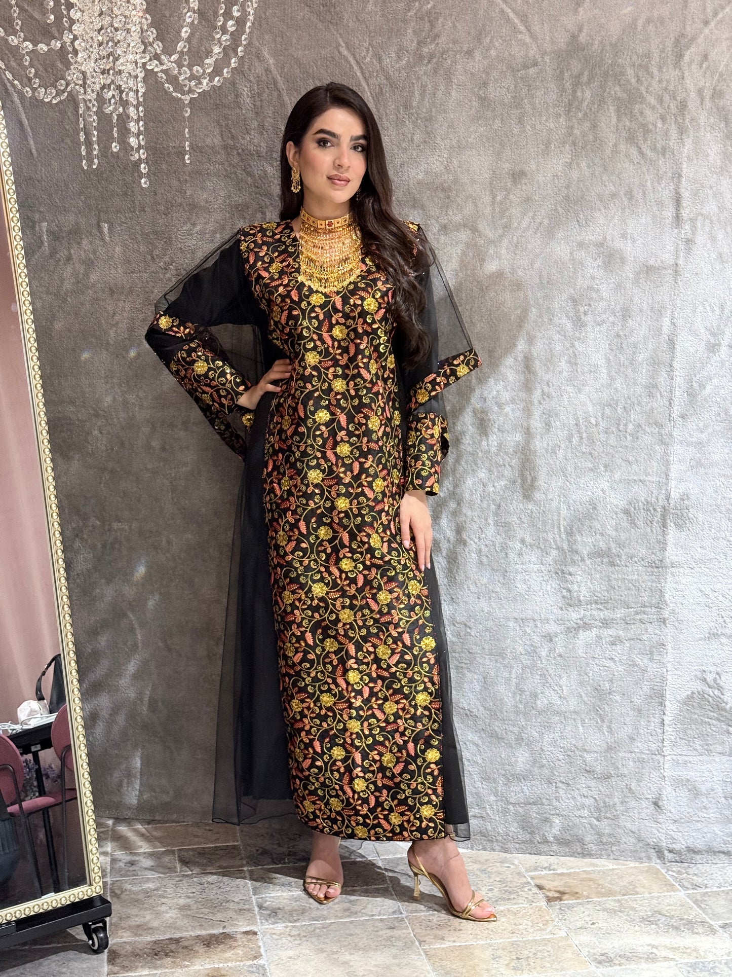 Woman in a black floral kaftan dress lying on a marble floor
