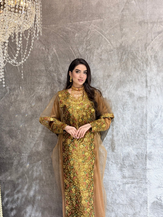 Woman in a Golden Brown Floral Embroidered Kaftan standing on a reflective floor with a chandelier in the background