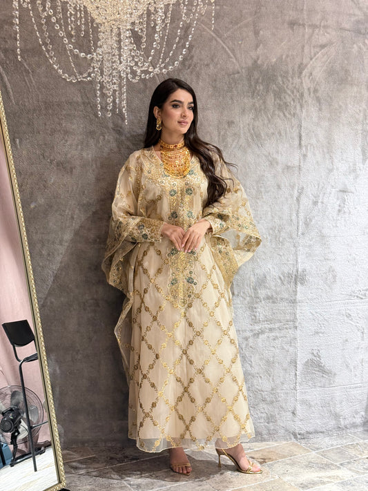 Woman wearing a traditional Beige Luxury Embroidered Kaftan outfit on a textured gray background