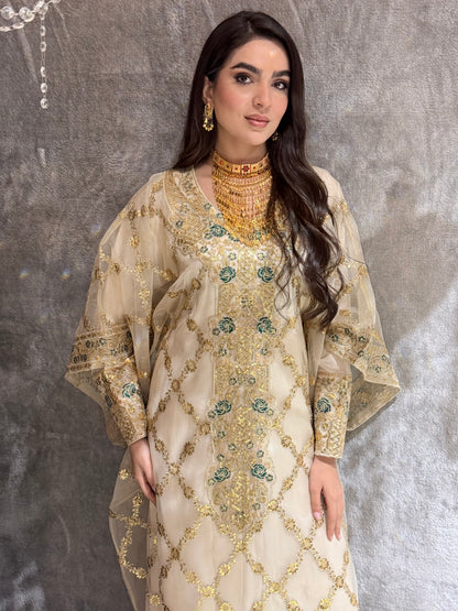 Woman wearing a traditional Beige Luxury Embroidered Kaftan outfit on a textured gray background