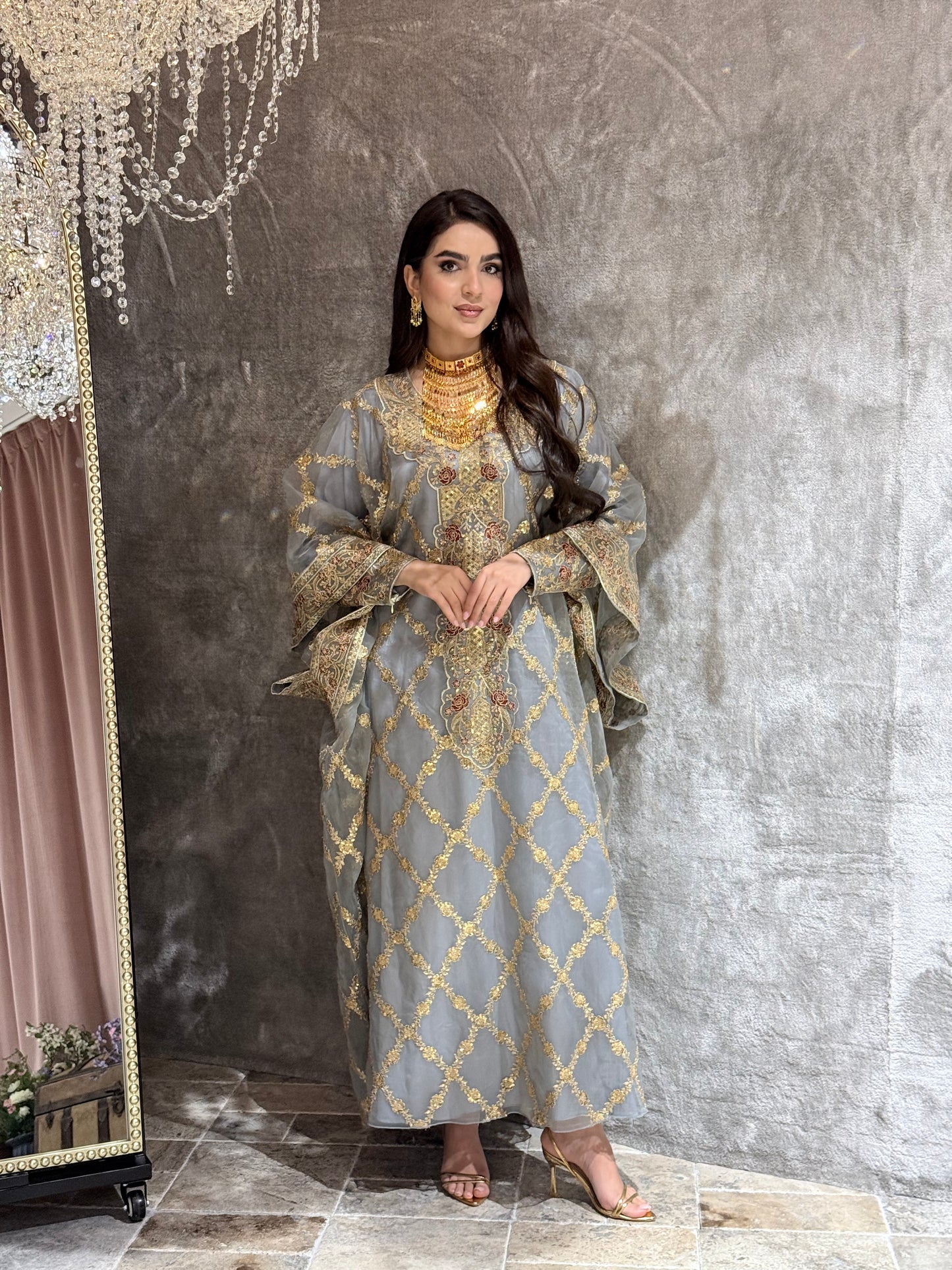 Woman wearing a Grey Luxury Embroidered Kaftan traditional outfit on a textured surface