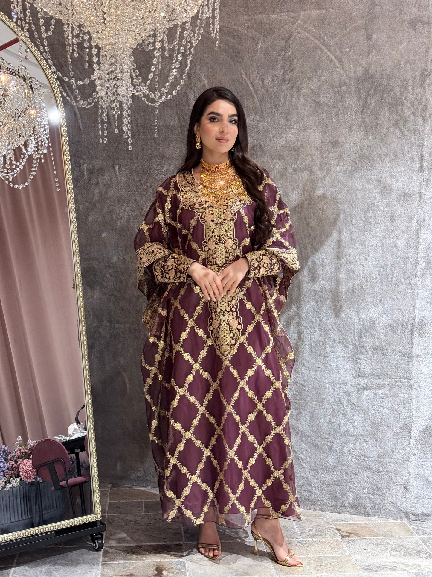 Woman in a Maroon Luxury Embroidered Kaftan traditional outfit standing on a textured surface.