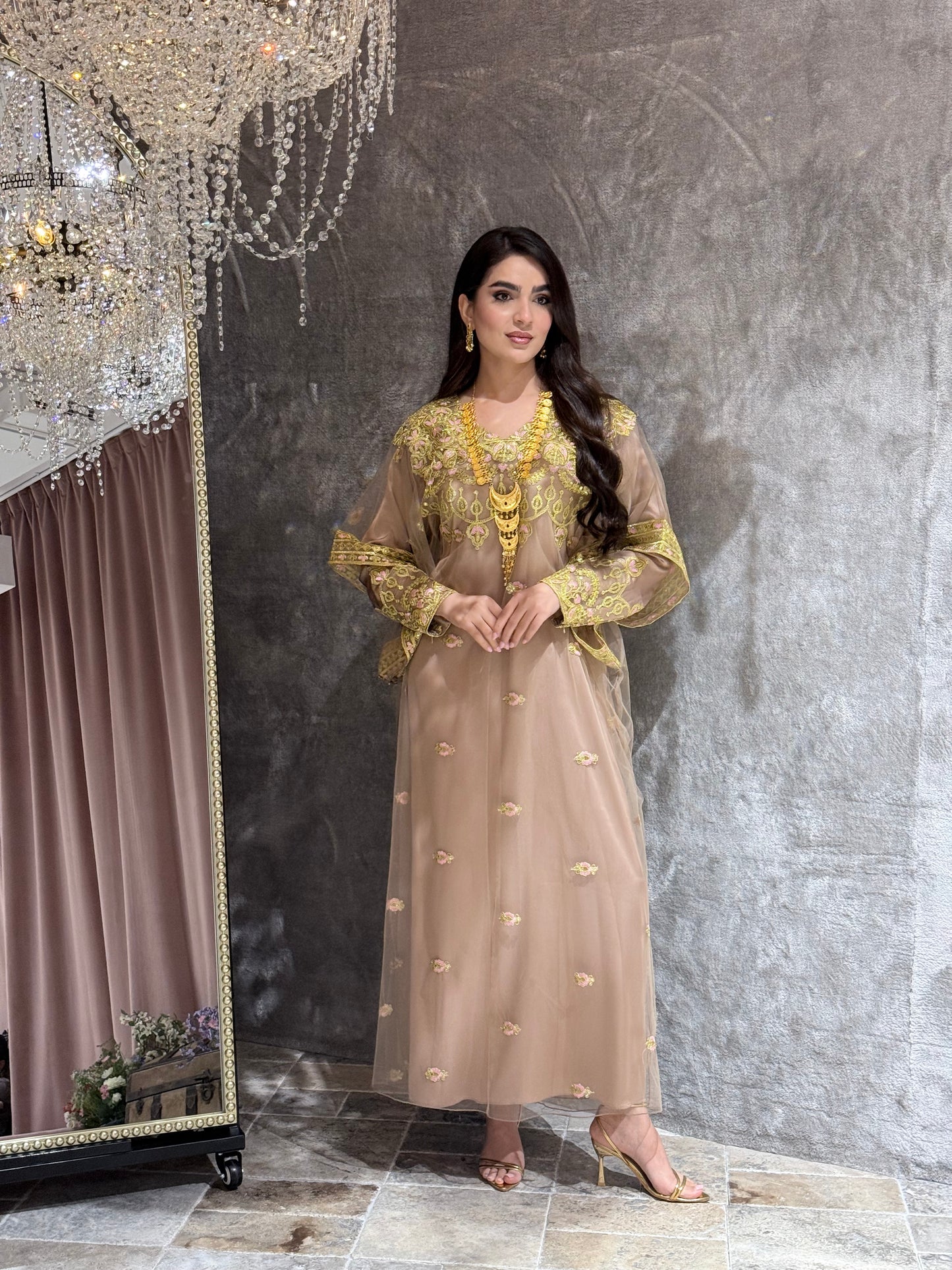 Woman in a Beige Luxury Embroidered Kaftan traditional outfit with gold embroidery lying on a textured surface