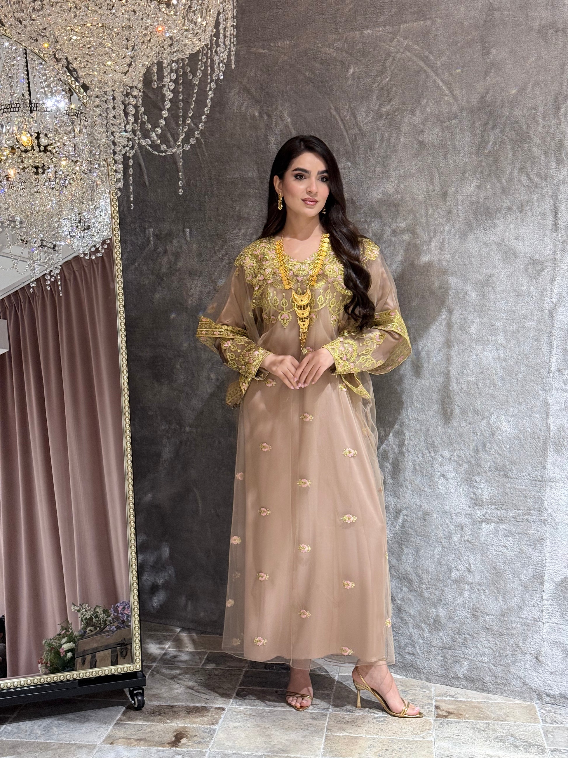 Woman in a Beige Luxury Embroidered Kaftan traditional outfit with gold embroidery lying on a textured surface
