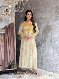 Woman in a Cream Luxury Embroidered Kaftan dress with gold accents standing in front of a mirror.