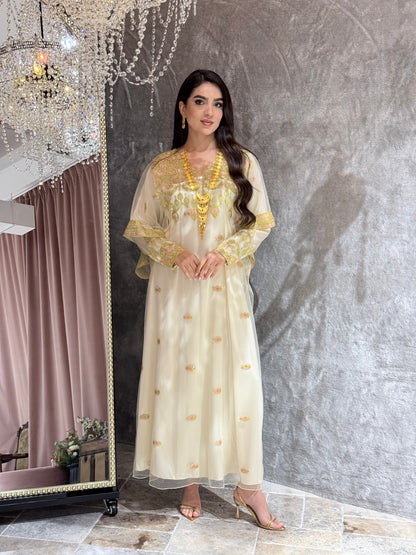 Woman in a Cream Luxury Embroidered Kaftan dress with gold accents standing in front of a mirror.
