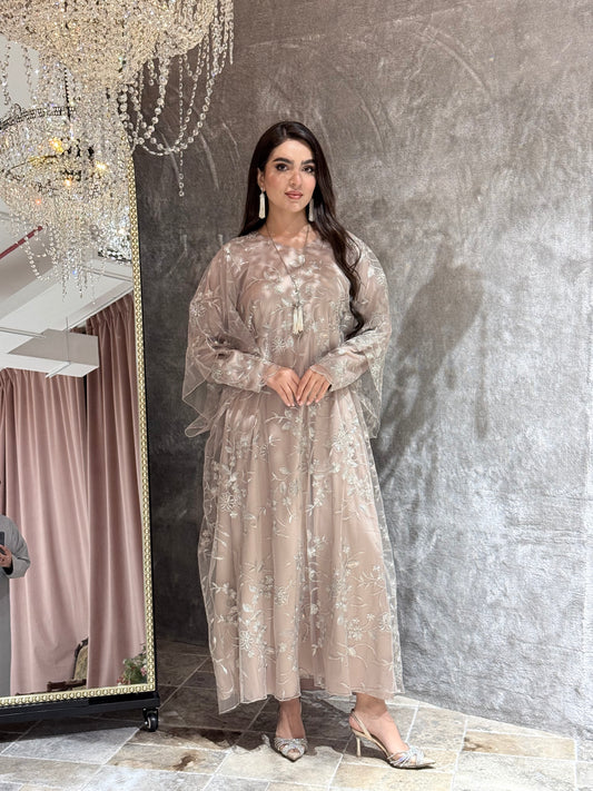 Woman in a Dusty Beige Floral Embroidered Kaftan standing in front of a mirror with a chandelier in the background